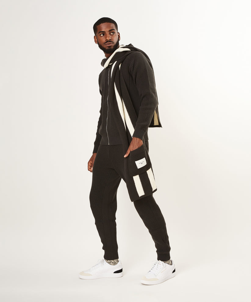 CUSTOM_ALT_TEXT: Male model wearing Paper Planes Zip-Up Knit Sweater and Sweater Knit Jogger, color Pirate Black.