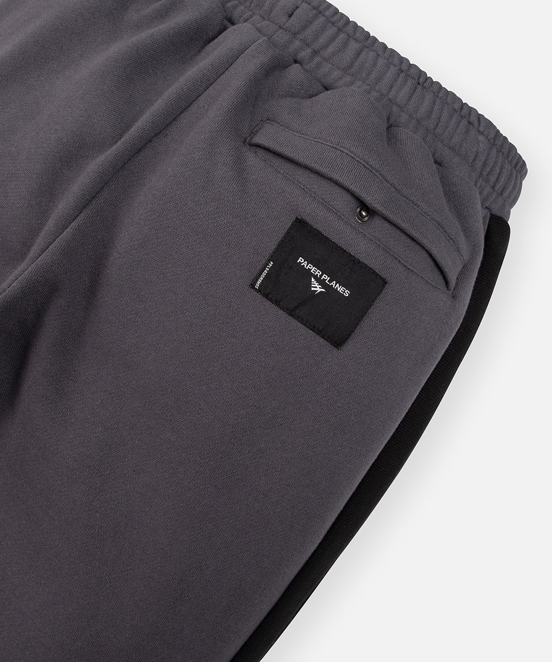 CUSTOM_ALT_TEXT: Back welt pocket with hidden snap and woven jacquard label on Paper Planes Dream Lab Sweatpant, color Asphalt.