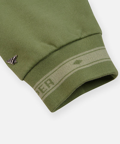 CUSTOM_ALT_TEXT: Plane metal with enamel rivet and jacquard logo cuff on Paper Planes Logo Jacquard Hoodie, color Bronze Green.