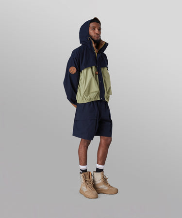CUSTOM_ALT_TEXT:Male model wearing Paper Planes Super Cargo Short color Indigo with Lovers & Friends Hooded Ripstop Jacket.